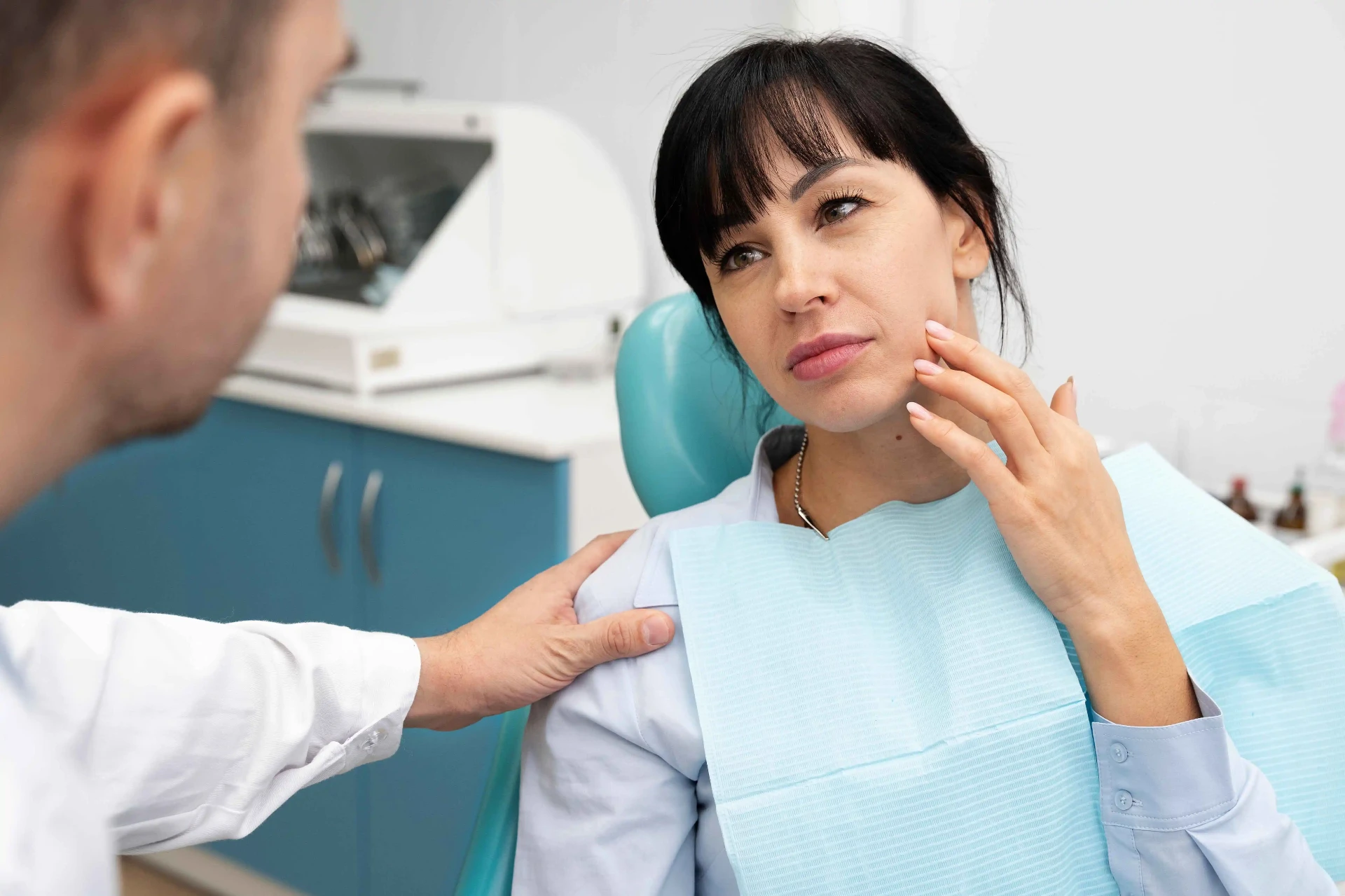 Cirurgião-dentista avaliando paciente com dor na mandíbula e suspeita de DTM em consultório odontológico em Curitiba